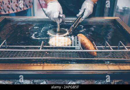 Frau, die Koreanisch Sweet Pancakes-Hotteok in heißem Öl brate Stockfoto