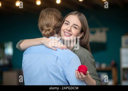 Frau, die einen Verlobungsring hält und einen Mann umarmt Stockfoto