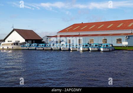 Eine Reihe von Tagesbooten, die auf einem Bootshof am Fluss Thurne auf dem Norfolk Broads an der Brücke in Potter Heigham, Norfolk, England, Großbritannien und Europa gefestigt wurden. Stockfoto