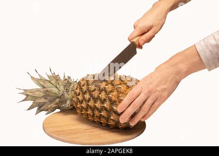 Männliche Hände schneiden und schälen frische Ananas dicht auf weißem Grund Stockfoto