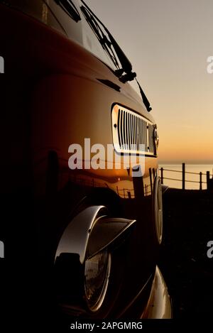 Ein geparktes VW Volkswagen Wohnwagen bei Sonnenaufgang/Sonnenuntergang. Hastings, East Sussex, England, Großbritannien Stockfoto