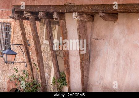 Holzbalken, die ein Mittelalterhaus mit roten Terrakotta-Wänden in Albarracin Teruel, Provinz Spanien, beherbergen Stockfoto