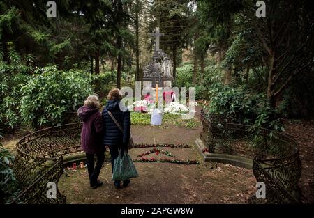 Hamburg, Deutschland. Januar 2020. Zwei Frauen besuchen das Grab des Schauspielers Jan Fedder auf dem Ohlsdorfer Friedhof. Davor hängt eine Kette und ein Schild mit der Aufschrift "Ich schlafe. Bitte nicht stören. Lassen Sie Ihre Blumen und Kerzen vorne. Das Zimmer vor dem Mahnmal ist mein Zimmer, nicht betreten!! Ta! Dein Jan'. Um die Pflanzen und den Rasen auf dem Grab des Schauspielers zu schützen, haben Friedhofsmitarbeiter eine Kette vor die Ruhestätte gelegt. (Zu dpa "Zerwürfnis am Fedder Grab - Friedhof legt Zeichen und Kette") Credit: Daniel Bockwoldt / dpa / Alamy Live News Stockfoto