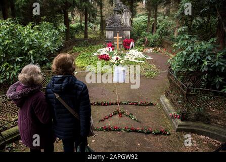 Hamburg, Deutschland. Januar 2020. Zwei Frauen besuchen das Grab des Schauspielers Jan Fedder auf dem Ohlsdorfer Friedhof. Davor hängt eine Kette und ein Schild mit der Aufschrift "Ich schlafe. Bitte nicht stören. Lassen Sie Ihre Blumen und Kerzen vorne. Das Zimmer vor dem Mahnmal ist mein Zimmer, nicht betreten!! Ta! Dein Jan'. Um die Pflanzen und den Rasen auf dem Grab des Schauspielers zu schützen, haben Friedhofsmitarbeiter eine Kette vor die Ruhestätte gelegt. (Zu dpa "Zerwürfnis am Fedder Grab - Friedhof legt Zeichen und Kette") Credit: Daniel Bockwoldt / dpa / Alamy Live News Stockfoto