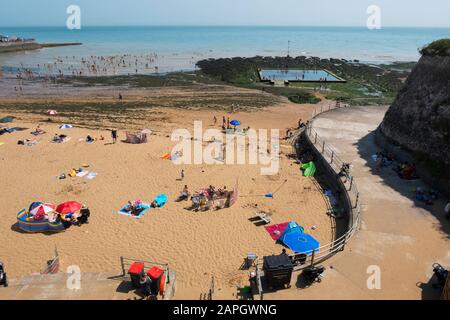 Menschen sonnen sich und Kinder spielen am Strand, natürliches Meerespool in den Felsen an der Viking Bay, Broadstairs, Kent, Großbritannien Stockfoto