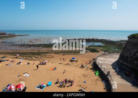 Menschen sonnen sich und Kinder spielen am Strand, natürliches Meerespool in den Felsen an der Viking Bay, Broadstairs, Kent, Großbritannien Stockfoto