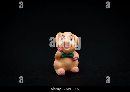 Nahaufnahme einer Figur mit einem kleinen, piggy sitzenden schwarzen Hintergrund Stockfoto