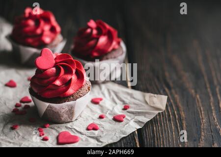 Valentine cupcakes in roter Farbe, mit süßen Herzen auf dunklen Holztisch eingerichtet. Für Text platzieren. Stockfoto