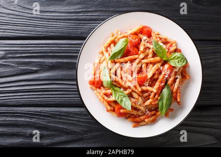 Pasta Trofie Rezept mit Tomatensauce, Parmesan und Basilikum Nahaufnahme in einem Teller auf dem Tisch. Horizontale Draufsicht von oben Stockfoto