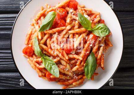 Servieren von Trofie-Pasta mit Tomatensauce, Käse und Basilikum in einem Teller auf dem Tisch. Horizontale Draufsicht von oben Stockfoto