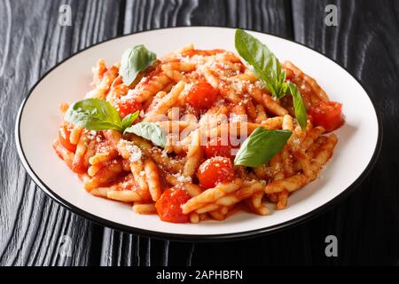 Traditionelle italienische Küche Trofie mit Tomatensauce, Parmesan und Basilikum in einem Teller auf dem Tisch. Horizontal Stockfoto