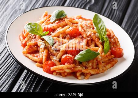 Ligurische Trofie-Pasta mit Tomatensauce, Parmesan und Basilikum in einem Teller auf dem Tisch. Horizontal Stockfoto