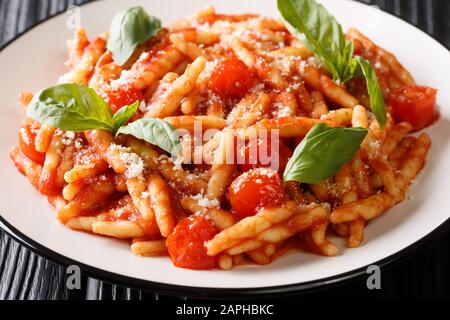 Servieren von Trofie-Pasta mit Tomatensauce, Käse und Basilikum in einem Teller auf dem Tisch. Horizontal Stockfoto