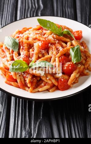 Leckere Trofie mit Tomatensauce, Käse und Basilikum in einem Teller auf dem Tisch. Vertikal Stockfoto