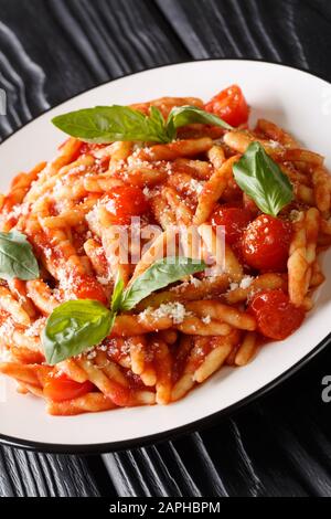 Italienische Trofie-Pasta mit Tomaten, Parmesan und Basilikum in einem Teller auf dem Tisch. Vertikal Stockfoto