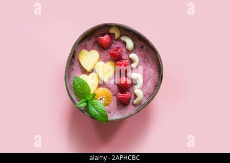 Gesundes Frühstück Banane und blueberry Smoothie mit Früchten in Coconut Schüssel auf rosa Hintergrund eingerichtet. Blick von oben. Sauber Essen, vegetarische fo Stockfoto
