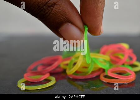 Mehrfarbige Gummibänder von Hand. Gummibänder und Finger. Gummibänder aus der Hand geworfen. Stockfoto