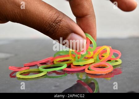 Mehrfarbige Gummibänder von Hand. Gummibänder und Finger. Gummibänder aus der Hand geworfen. Stockfoto