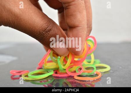 Mehrfarbige Gummibänder von Hand. Gummibänder und Finger. Gummibänder aus der Hand geworfen. Stockfoto