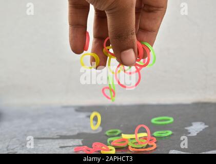 Mehrfarbige Gummibänder, die von Hand und im freien Fall aufgenommen wurden. Gummibänder und Finger. Gummibänder aus der Hand geworfen. Stockfoto