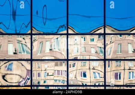 Krumme Reflexion von Häusern im Glas des Fensters abstrakter farbiger Hintergrund Stockfoto