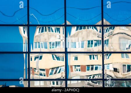 Krumme Reflexion von Häusern im Glas des Fensters abstrakter farbiger Hintergrund Stockfoto