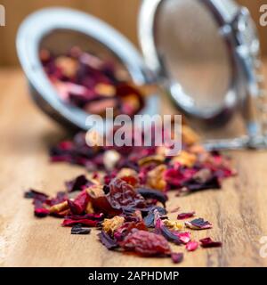 Eckige Früchte haben roten Beerentee mit Orangen- und apfelschale infundiert, Holzhintergrund extrem selektiv auf den Mittelgrund fokussiert, um Platz für Kopien zu schaffen Stockfoto