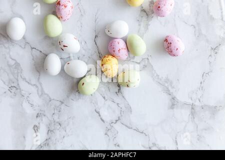 Frohe Ostern Konzept. Vorbereitung für den Urlaub. Ostern Eier in Pastellfarben Süßigkeiten Schokolade Bonbons auf trendige grauem Marmor Hintergrund. Einfache Minimalismus flach Ansicht von oben kopieren Raum Stockfoto