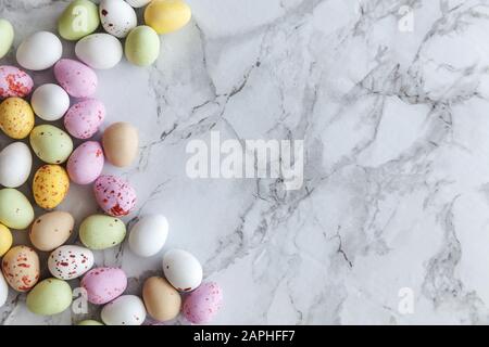 Frohe Ostern Konzept. Vorbereitung für den Urlaub. Ostern Eier in Pastellfarben Süßigkeiten Schokolade Bonbons auf trendige grauem Marmor Hintergrund. Einfache Minimalismus flach Ansicht von oben kopieren Raum Stockfoto