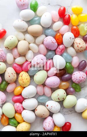 Frohe Ostern Konzept. Vorbereitung für den Urlaub. Ostern Süßigkeiten Schokolade Eier und fruchtgummi Bonbons auf trendige grauem Marmor Hintergrund. Einfache Minimalismus flach Ansicht von oben kopieren Raum Stockfoto