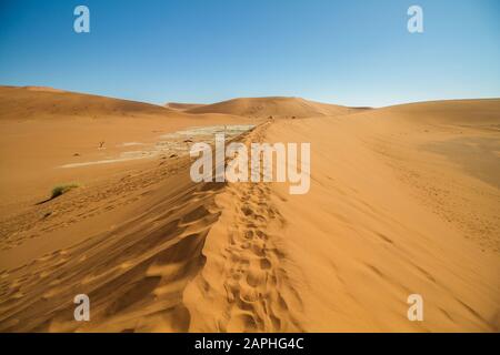 Landschaft von Deadvlei von einer Düne mit Fußabdrücken im Sand in Sossusvlei, Namibia Stockfoto