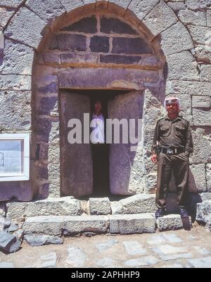 Jordanien. Ein Touristenpolizist und Reiseleiter steht an der Eingangstür zum Innenhof der Festung Qasr Al Azraq in der nördlichen Wüste Jordaniens. Beachten Sie die Größe der schweren Steintüren. Die verlassene Festung wurde während seiner arabischen Studien, die er mit den örtlichen Beduinern teilte, als Basis für T. -E.-Lawrence genutzt, bevor er während der arabischen Revolte gegen das türkische Osmanische Reich während des Ersten Weltkriegs als Lawrence von Arabien Ruhm erlangte Stockfoto