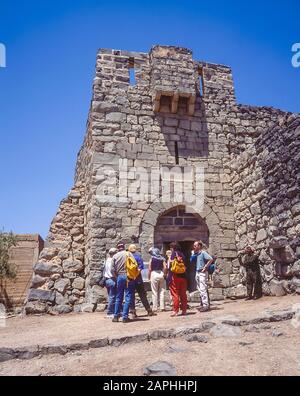 Jordanien. Eine Gruppe europäischer Touristen wartet auf den Innenhof der Festung Qasr Al Azraq in der nördlichen Wüste Jordaniens. Die verlassene Festung wurde während seiner arabischen Studien, die er mit den örtlichen Beduinern teilte, als Basis für T. -E.-Lawrence genutzt, bevor er während der arabischen Revolte gegen das türkische Osmanische Reich während des Ersten Weltkriegs als Lawrence von Arabien Ruhm erlangte Stockfoto