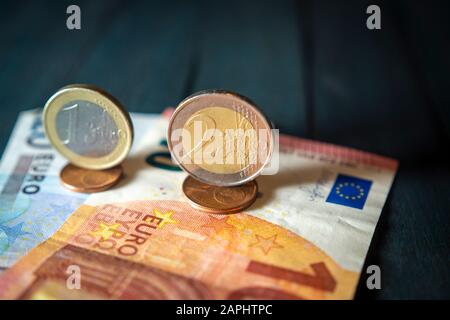 Nahaufnahme von Euro-Bargeld mit verschiedenen Euro-Münzen und Cents über Banknoten auf schwarzem Holztisch. Starkes und stabiles Währungskonzept mit VARIET Stockfoto