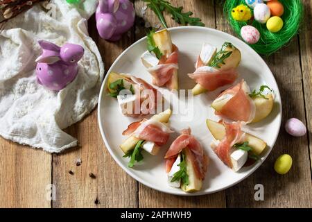 Festliche Snacks. Birnen-Vorspeise mit Jamon, Arugula und brie-käse auf einem rustikalen Holztisch. Stockfoto