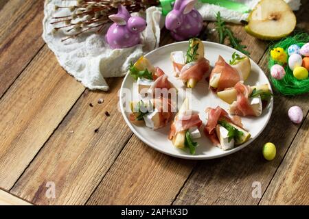 Festliche Snacks. Birnen-Vorspeise mit Jamon, Arugula und brie-käse auf einem rustikalen Holztisch. Kopierbereich. Stockfoto