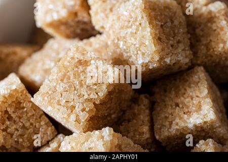 Nahaufnahme (Makro) von braunen Zuckerwürfeln, die zusammengehüpft werden. Stockfoto