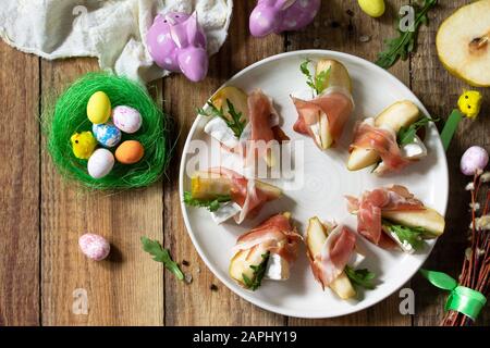 Festliche Snacks. Birnen-Vorspeise mit Jamon, Arugula und brie-käse auf einem rustikalen Holztisch. Flacher Laienhintergrund in der Draufsicht. Stockfoto