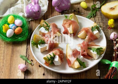 Festliche Snacks. Birnen-Vorspeise mit Jamon, Arugula und brie-käse auf einem rustikalen Holztisch. Stockfoto