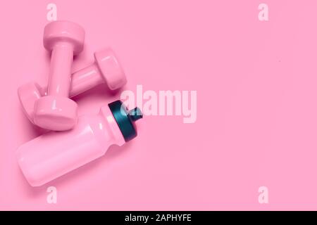 Fitness-Workout-Hintergrundkonzept mit pinkfarbenen Hanteln und einer Flasche Wasser. Top View Flachlaiensport, Ernährung und gesunder Lebensstil mit Trainingsausrüstung Stockfoto
