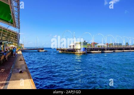 Willemstad, Curacao, Niederlande - 5. Dezember 2019: Menschen an der Queen Emma Bridge vor dem Stadtteil Punda, ist eine Pontonbrücke über St. Anna B. Stockfoto