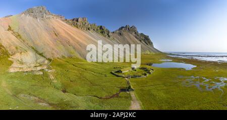 Isländische Luftlandschaften mit einem wikingerdorf in Stokksnes. Panorama auf den Vestrahorn-Berg an einem sonnigen Tag. Stockfoto