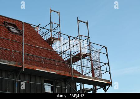 Dach eines renovierungsbedürftigen Hauses mit einem Metallgerüst mit Sicherheitsnetz Stockfoto