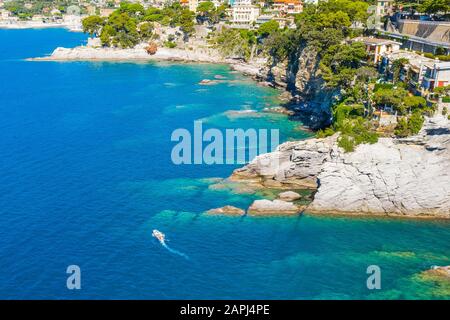 Weißen Segeln in der Nähe von felsigen Küste in Camogli, Italien. Luftaufnahme auf die Adria, Ligurien. Stockfoto