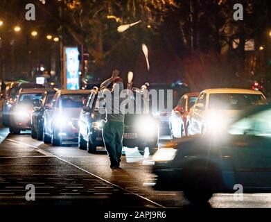 23. Januar 2020, Hessen, Frankfurt am Main: Am Abend führt ein Straßenkünstler seine Tricks vor den Haltewagen an einer vielbefahrenen Kreuzung am Allenring durch, für die er auch in der kurzen roten Ampelphase schnell eine Spende zu sammeln versucht. Foto: Frank Rumpenhorst / dpa Stockfoto