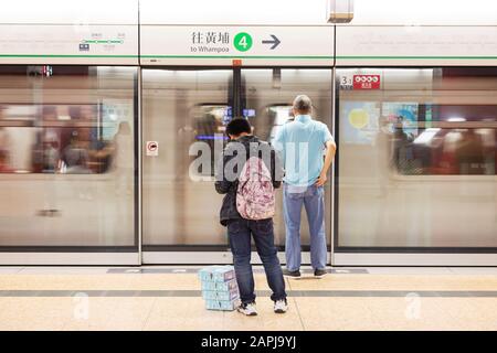 Zug Hongkong - Passagiere auf dem Bahnsteig, während ein Zug am Bahnhof Mong Kok der MTR Hongkong - Mass Transit Railway in Hongkong Asia anfährt Stockfoto