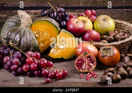 Stillleben mit Früchten und Herbstfarben auf rustikalem Holztisch Stockfoto