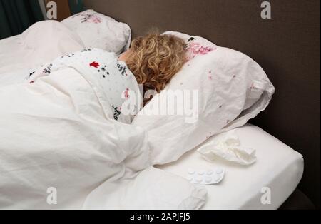 Eine Frau liegt im Bett mit Grippe während einer Grippeepidemie Stockfoto