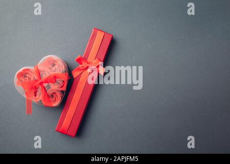 Valentinstag Geschenke. Roter Geschenkkasten und herzförmige Schachtel mit Seifenrosen Stockfoto