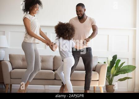 Lustige aktive Familie mit kleinen Kindern, die im Wohnzimmer tanzt Stockfoto